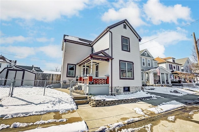 view of front of house with covered porch, a fenced front yard, and a residential view