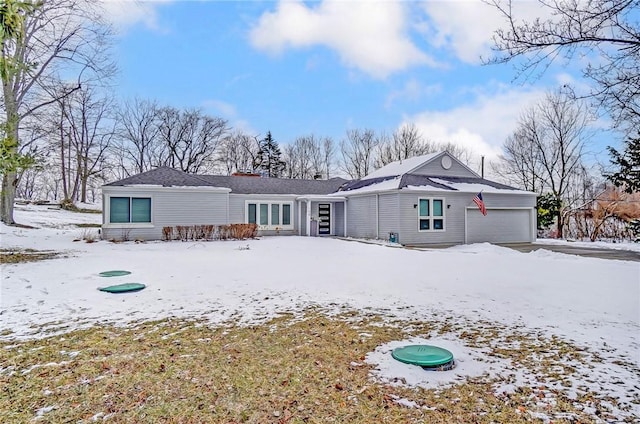 snow covered rear of property featuring a garage