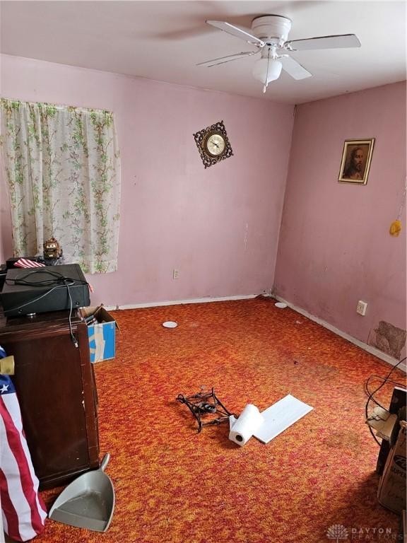 interior space featuring a ceiling fan, carpet, and baseboards