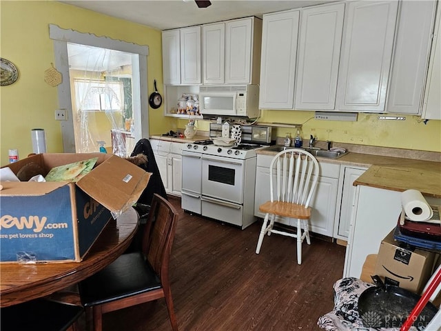 kitchen featuring white appliances, a sink, white cabinets, light countertops, and dark wood-style floors