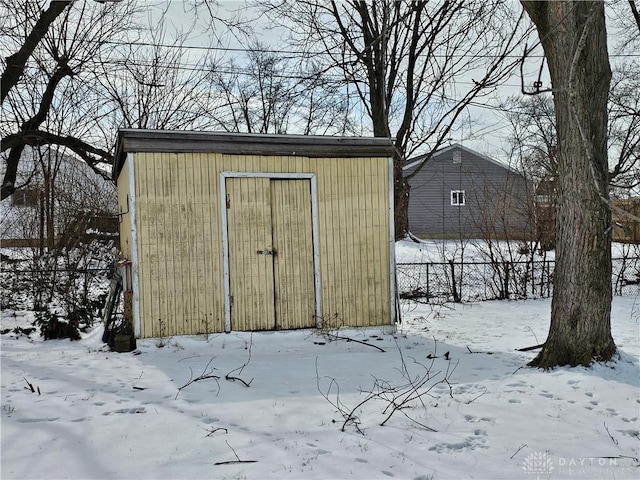 snow covered structure featuring a garage and fence