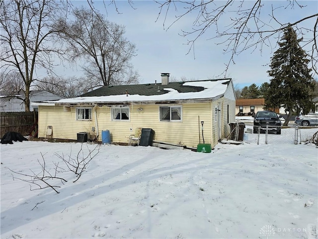 snow covered rear of property with fence