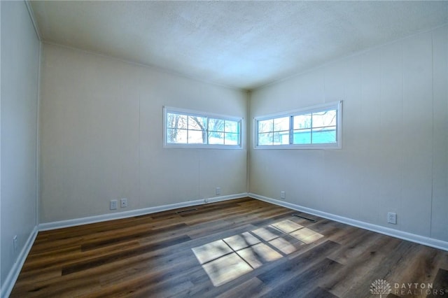 empty room featuring dark wood-style floors, baseboards, and a textured ceiling