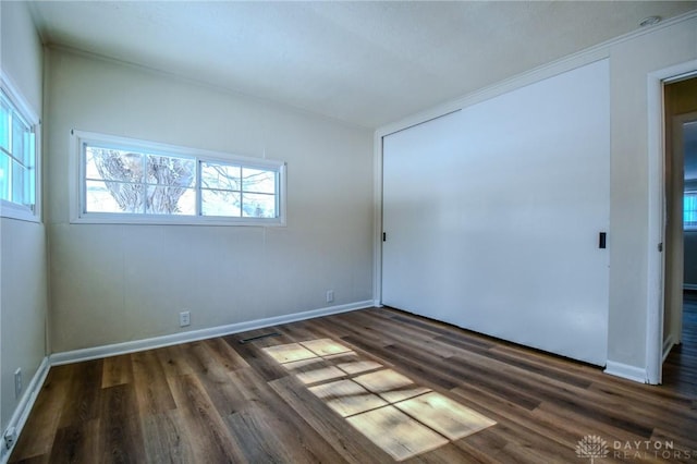 empty room with dark wood-style flooring and baseboards