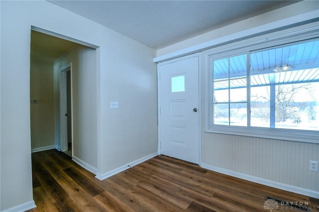 foyer with dark wood-style flooring and baseboards