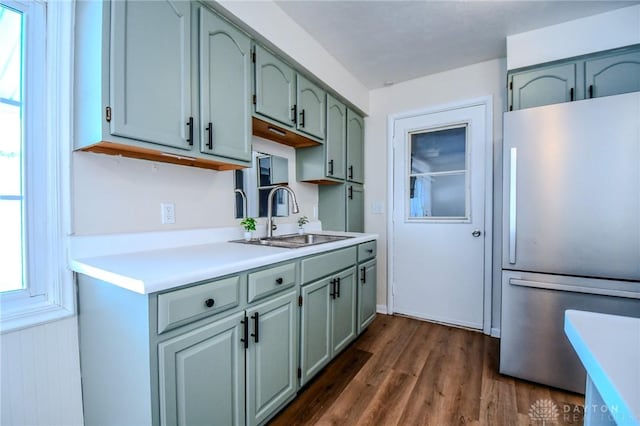 kitchen with light countertops, dark wood-style flooring, a sink, and freestanding refrigerator