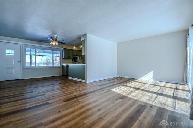 unfurnished living room with baseboards, dark wood finished floors, and a ceiling fan