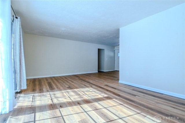 empty room featuring baseboards and light wood finished floors