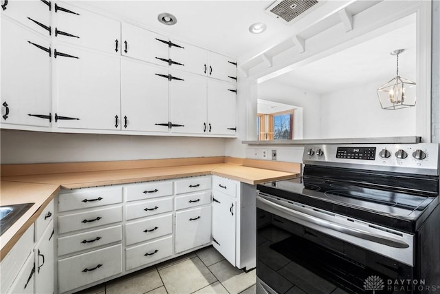 kitchen featuring stainless steel electric range oven, light countertops, hanging light fixtures, and white cabinets