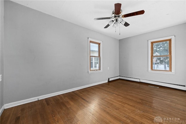 unfurnished room featuring baseboard heating, ceiling fan, baseboards, and wood finished floors