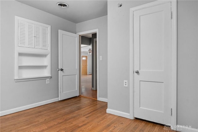 unfurnished bedroom with visible vents, baseboards, and wood finished floors