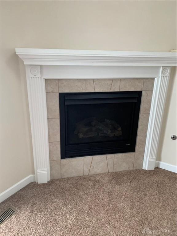 room details with carpet, baseboards, visible vents, and a tiled fireplace