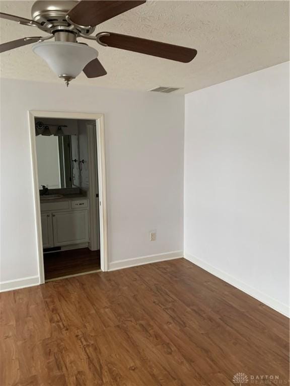 unfurnished room with a textured ceiling, dark wood finished floors, and visible vents