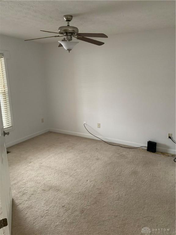 unfurnished room featuring carpet, baseboards, and a ceiling fan