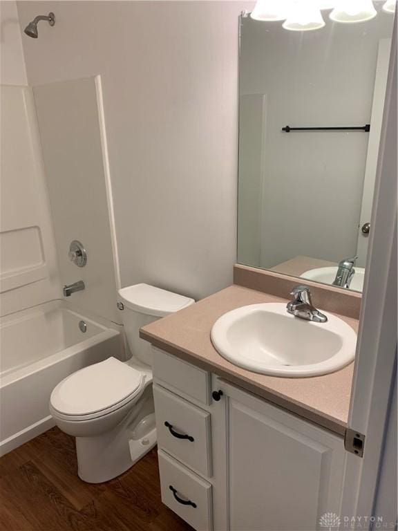 bathroom with toilet, shower / tub combination, wood finished floors, and vanity