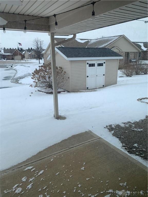 yard layered in snow featuring a storage shed and an outdoor structure