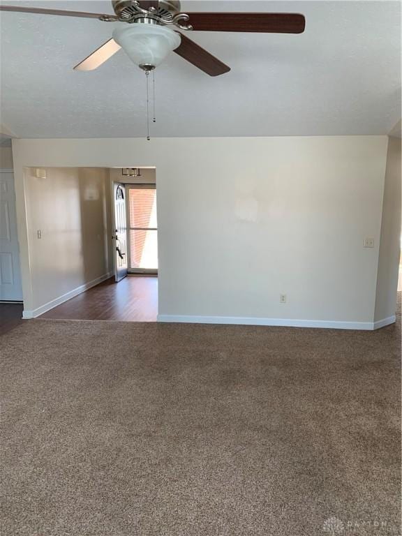 empty room featuring baseboards, dark carpet, and ceiling fan