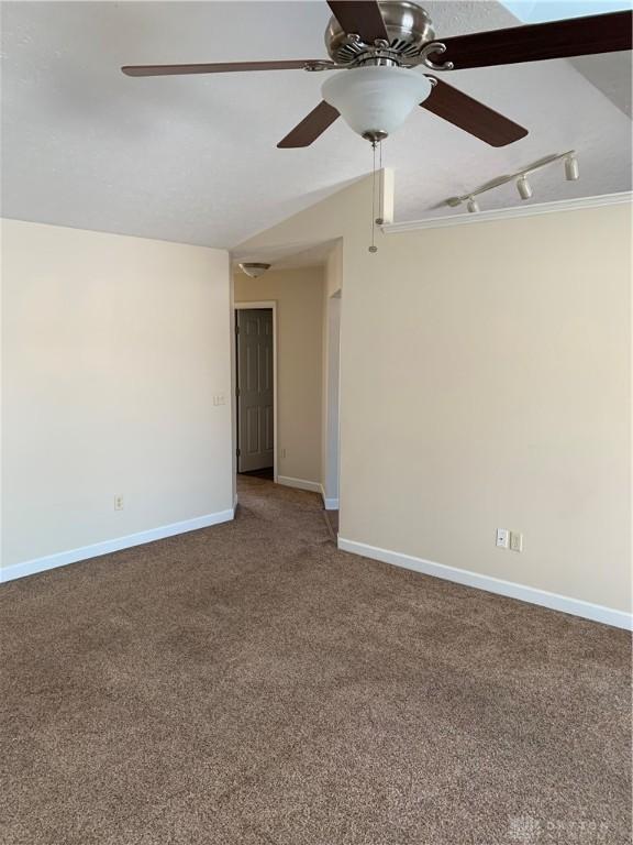 carpeted spare room with track lighting, baseboards, and a ceiling fan