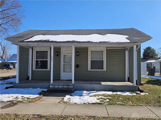 bungalow with a porch and roof with shingles