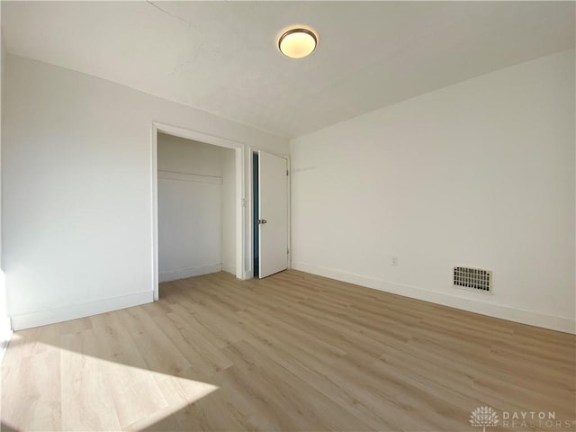 unfurnished bedroom with light wood-style floors, a closet, visible vents, and baseboards