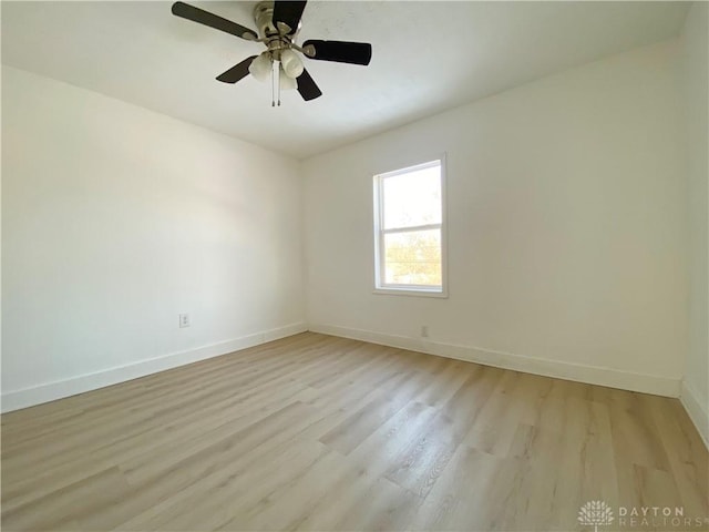 empty room with baseboards, ceiling fan, and light wood-style floors