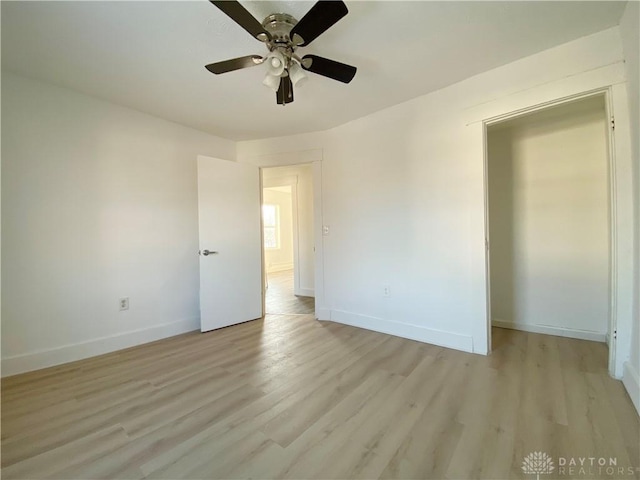 empty room featuring a ceiling fan, light wood-type flooring, and baseboards