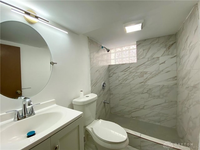 full bathroom featuring tiled shower, vanity, and toilet