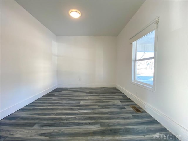 spare room featuring dark wood-style floors and baseboards