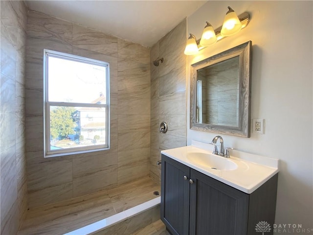 bathroom with tiled shower and vanity