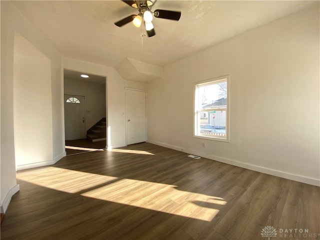 unfurnished room featuring stairs, baseboards, dark wood finished floors, and a ceiling fan