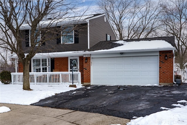 view of front facade featuring an attached garage, brick siding, covered porch, and driveway