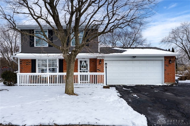 traditional-style home with a garage, brick siding, covered porch, and driveway