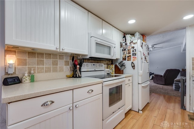 kitchen with tasteful backsplash, light countertops, light wood-style floors, white cabinets, and white appliances