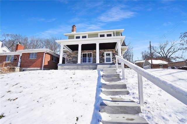 view of front facade with stone siding, covered porch, and a chimney