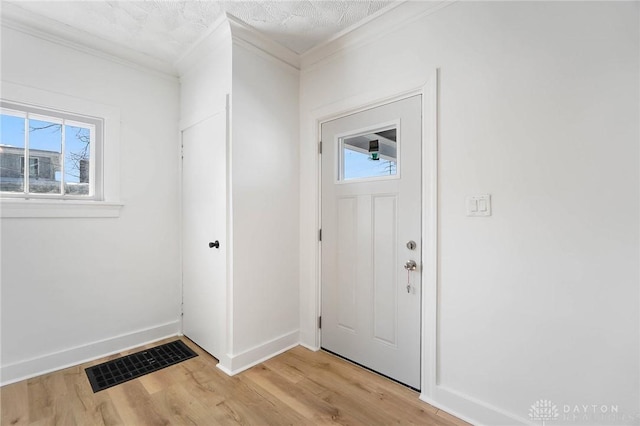 foyer entrance with ornamental molding, a wealth of natural light, and visible vents