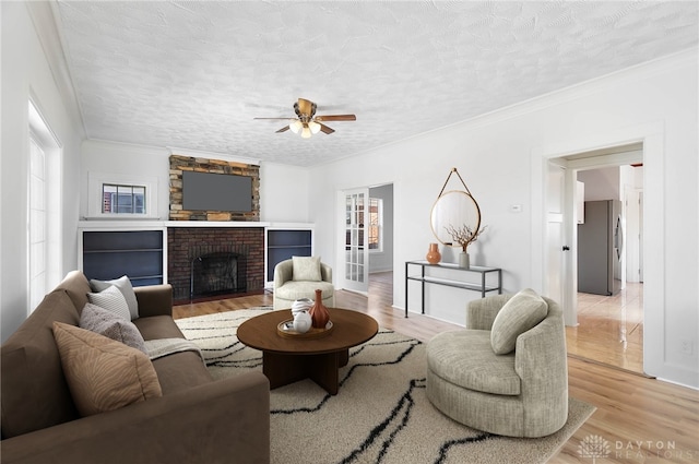 living area with light wood-type flooring, ornamental molding, and a textured ceiling