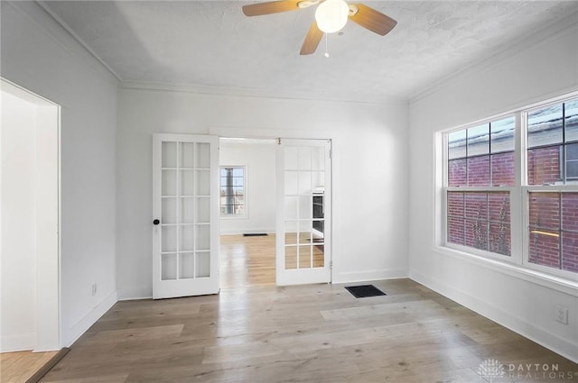 unfurnished room with ornamental molding, french doors, baseboards, and light wood-style floors