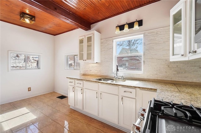 kitchen with glass insert cabinets, white cabinetry, a sink, and decorative backsplash