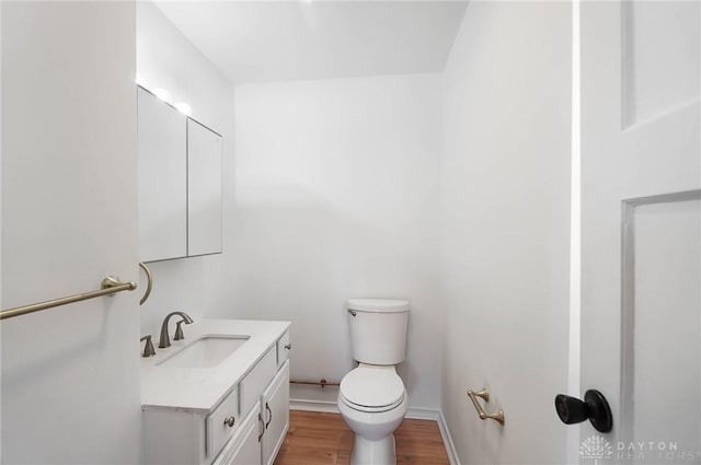 bathroom featuring toilet, baseboards, wood finished floors, and vanity