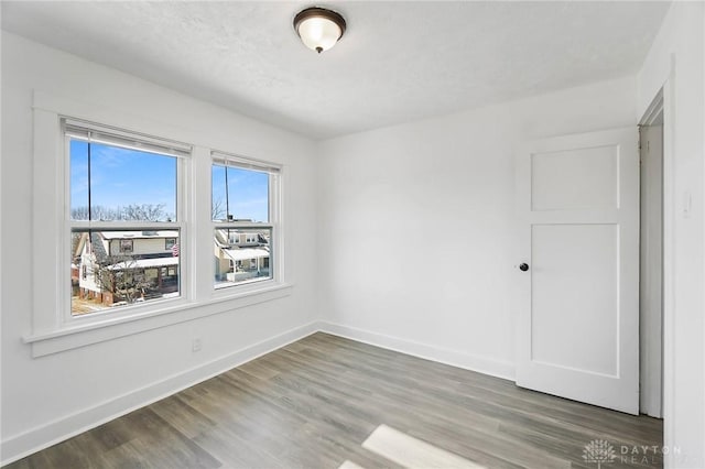 spare room with dark wood-type flooring and baseboards