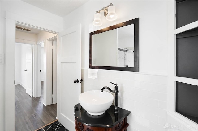 bathroom featuring vanity, wood finished floors, visible vents, and tile walls