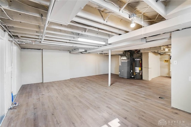 finished basement with gas water heater, wood finished floors, and heating unit