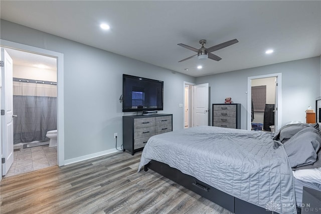 bedroom with connected bathroom, recessed lighting, wood finished floors, baseboards, and a spacious closet