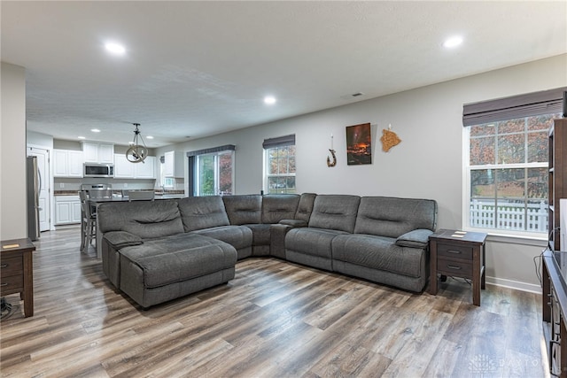 living room featuring baseboards, visible vents, wood finished floors, and recessed lighting