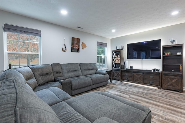 living room with light wood-style floors, visible vents, a textured ceiling, and recessed lighting