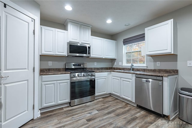 kitchen with stainless steel appliances, dark countertops, and white cabinetry