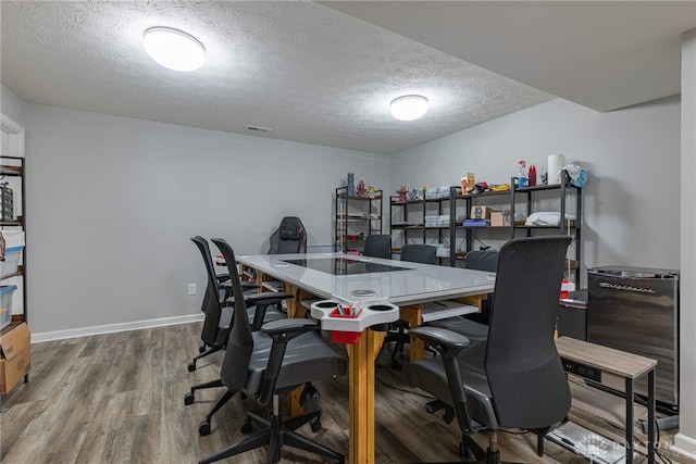 office area featuring visible vents, a textured ceiling, baseboards, and wood finished floors