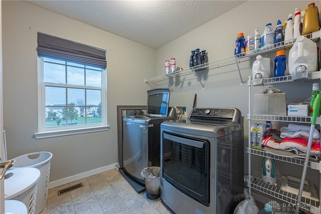 laundry area with a textured ceiling, laundry area, visible vents, baseboards, and washer and dryer