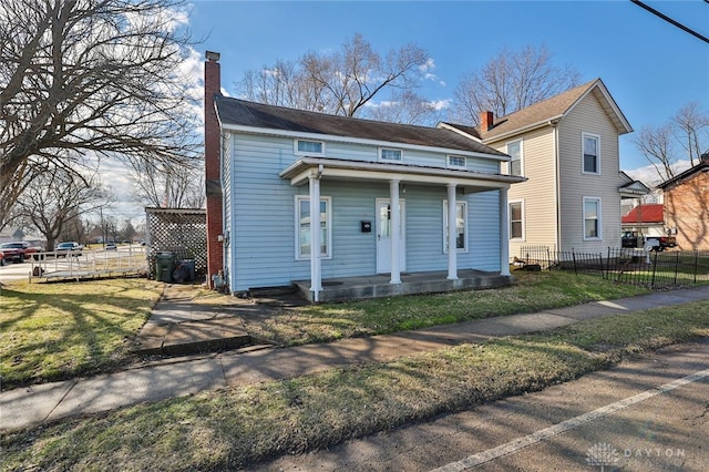 view of front of house with a front lawn, a chimney, and fence