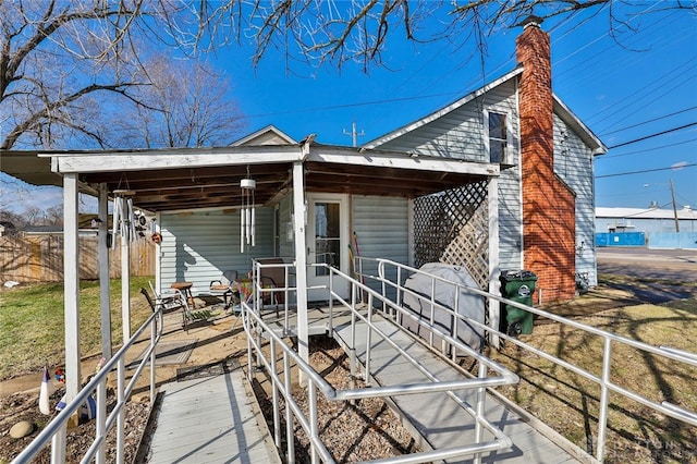 rear view of property featuring a chimney and fence